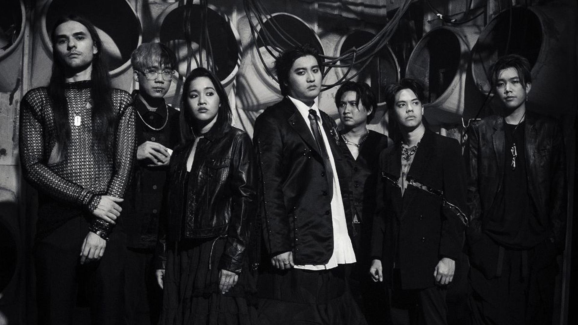 Black and white image featuring the seven members of the metal band Defying Decay standing next to each other wearing dark costumes.