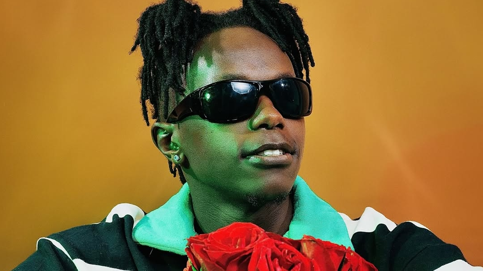 Young male artists with pony tails wearing sun glasses in front of an yellow-red backdrop.